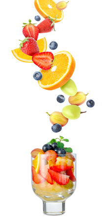 Delicious fruit salad in glass and flying ingredients on white backgroundの写真素材