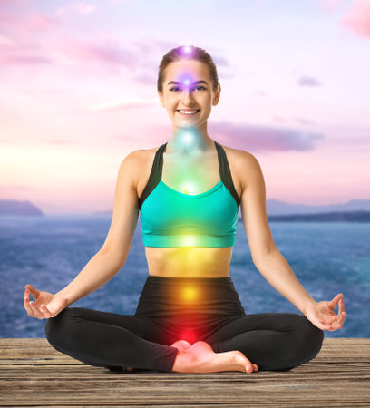 Beautiful young woman practicing yoga near sea