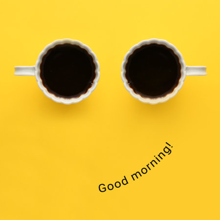 Cups of coffee and phrase GOOD MORNING on color background