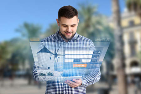 Young man with tablet computer booking tickets online at tropical resort