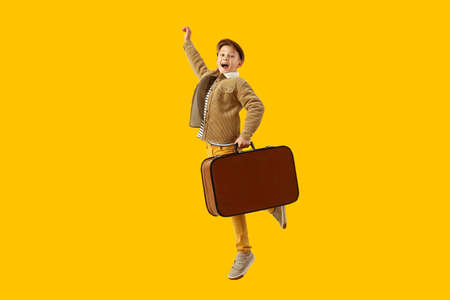 Jumping little tourist with suitcase on color backgroundの写真素材