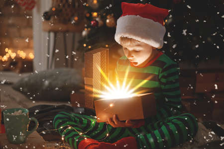 Cute little boy opening magic Christmas gift at homeの写真素材