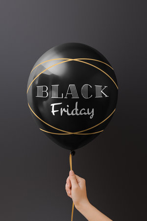 Female hand holding air balloon with text "Back Friday" on dark backgroundの写真素材