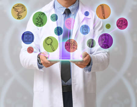 Male doctor with tablet computer on gray background. Concept of modern technologies in medicine