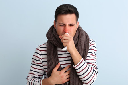 Ill young man with runny nose on color backgroundの写真素材