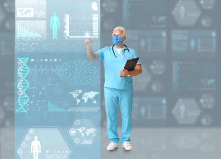 Mature male doctor using virtual screen on dark background
