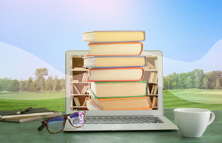 Modern laptop with books on table in park. Concept of online library