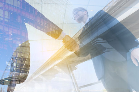 Double exposure of business partners shaking hands and modern city. Concept of business consultingの写真素材