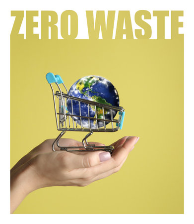 Female hand with small planet Earth in shopping cart on color background. Zero waste conceptの写真素材