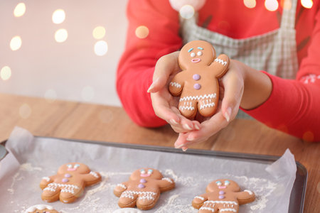 Young woman with tasty homemade gingerbread cookies in kitchen on Christmas eveの写真素材