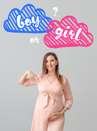 Beautiful pregnant woman thinking about sex of her baby on gray backgroundの写真素材
