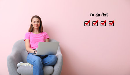 Young woman with laptop making to do list at home