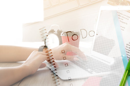 Young woman with laptop making to do list at homeの写真素材