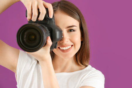 Young female photographer on color background