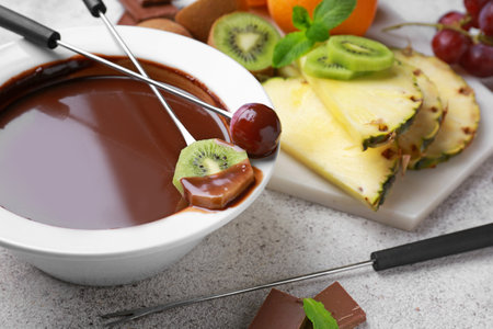 Bowl with tasty chocolate fondue and fruits on tableの写真素材