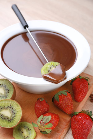 Bowl with tasty chocolate fondue, kiwi and strawberry on tableの写真素材