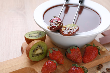 Bowl with tasty chocolate fondue, kiwi and strawberry on tableの写真素材