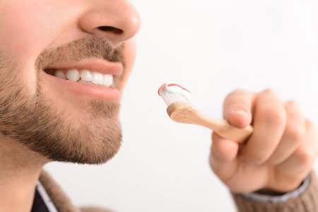 Handsome man with toothbrush and paste on light background, closeupの写真素材