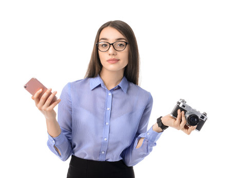 Thoughtful young businesswoman with mobile phone and photo camera on white backgroundの写真素材