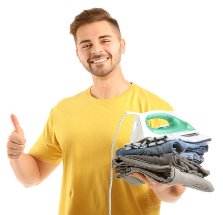 Young man with iron and clothes showing thumb-up gesture on white backgroundの写真素材