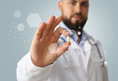 Male doctor holding pill on gray background, closeupの写真素材