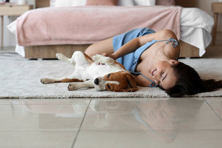 Young woman with cute dog lying on floor at homeの写真素材