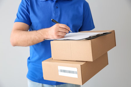 Delivery man with boxes on light background