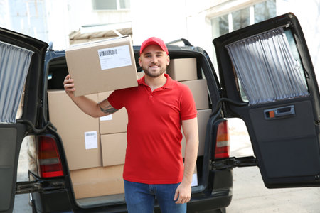 Handsome delivery man near car with parcels outdoorsの写真素材