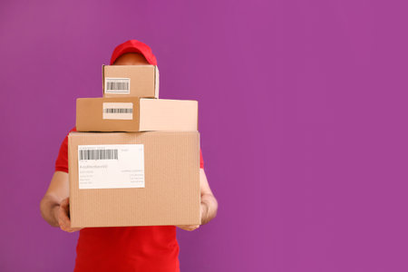 Delivery man with boxes on color backgroundの写真素材