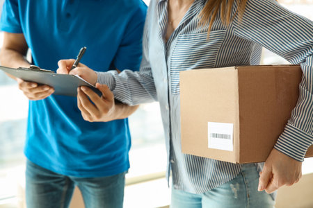 Woman signing documents to confirm receiving of order from delivery companyの写真素材