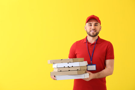 Handsome delivery man with pizza boxes on color backgroundの写真素材