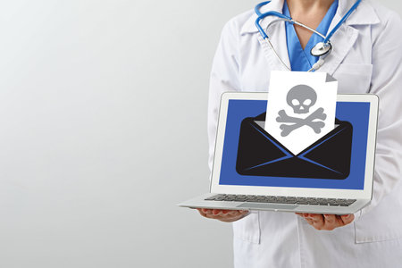 Female doctor with received infected email message on screen of laptop against light background