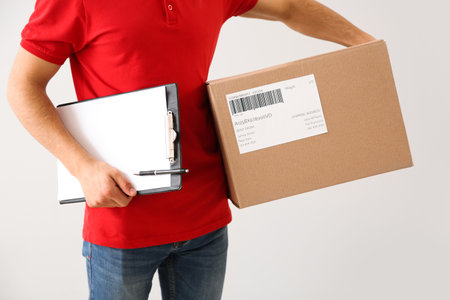 Delivery man with box and clipboard on white backgroundの写真素材