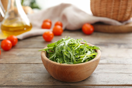 Bowl with tasty fresh arugula on wooden tableの写真素材