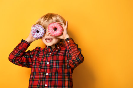 Happy little boy with tasty donuts on color backgroundの写真素材