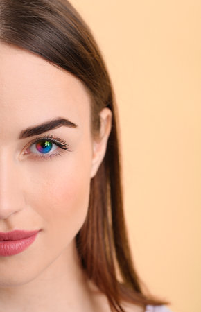 Beautiful young wearing rainbow contact lenses on color backgroundの写真素材