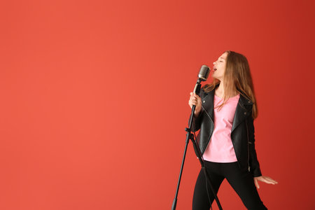 Teenage girl with microphone singing against color backgroundの写真素材