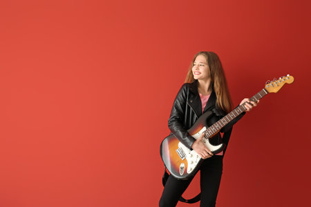 Teenage girl playing guitar against color background