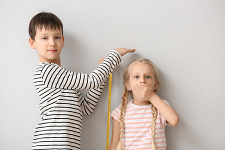 Cute little children measuring height near wall