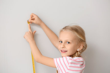 Cute little girl measuring height near wallの写真素材