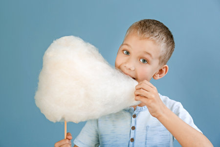 Cute little boy with cotton candy on color backgroundの写真素材
