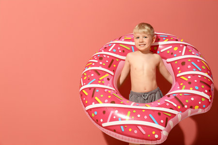 Cute little boy with inflatable ring on color backgroundの写真素材