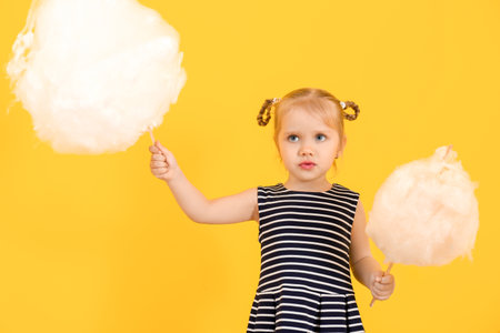 Cute little girl with cotton candy on color backgroundの写真素材