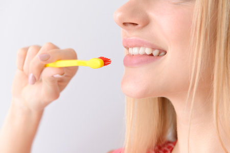 Woman with toothbrush on light background, closeup. Concept of dental hygieneの写真素材