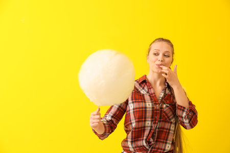 Beautiful woman with cotton candy on color background