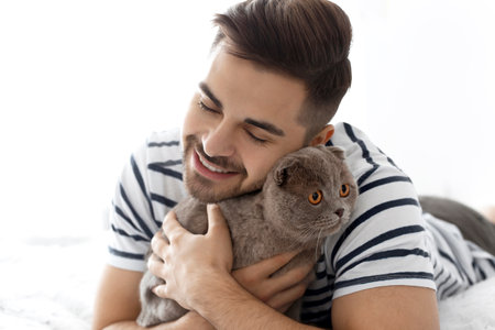 Young man with cute funny cat at homeの写真素材