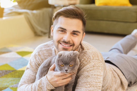 Young man with cute funny cat at homeの写真素材