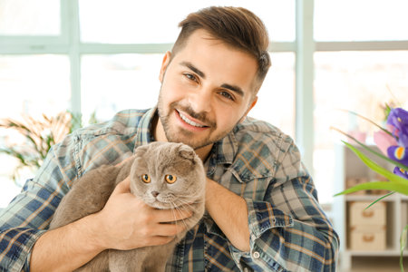 Young man with cute funny cat at homeの写真素材
