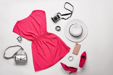 Set of female clothes, accessories and photo camera on white background