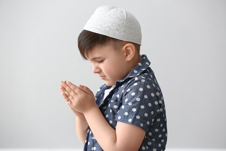 Little Muslim boy praying against light backgroundの写真素材